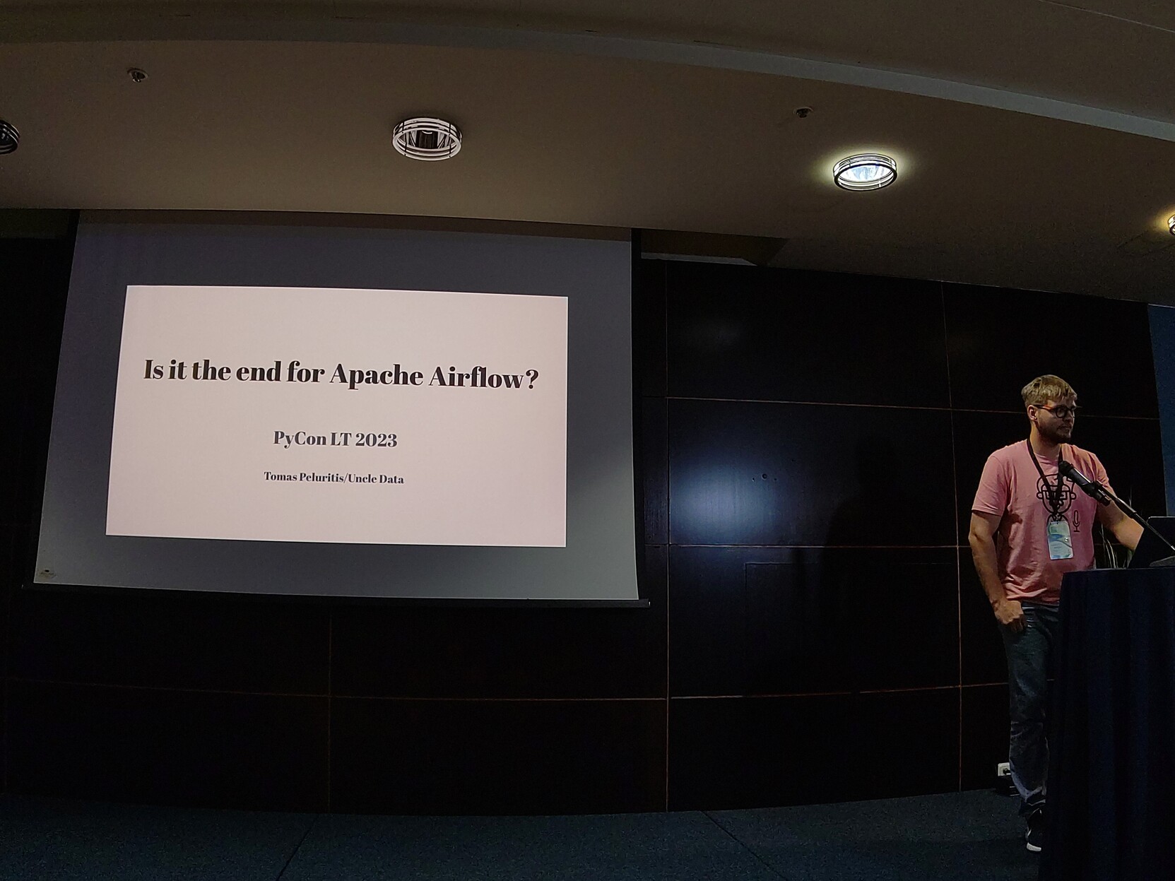 Photo of Tomas standing next to a screen, presenting 