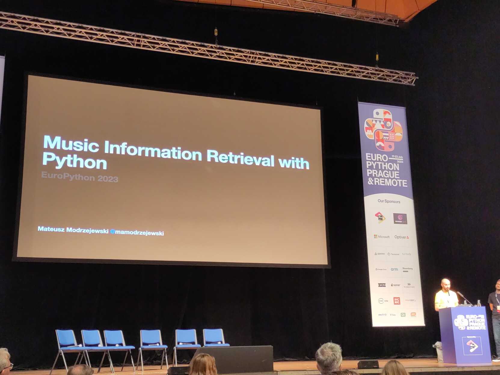 Photo of a man standing next to a slide titled "Music Information Retrieval with Python"