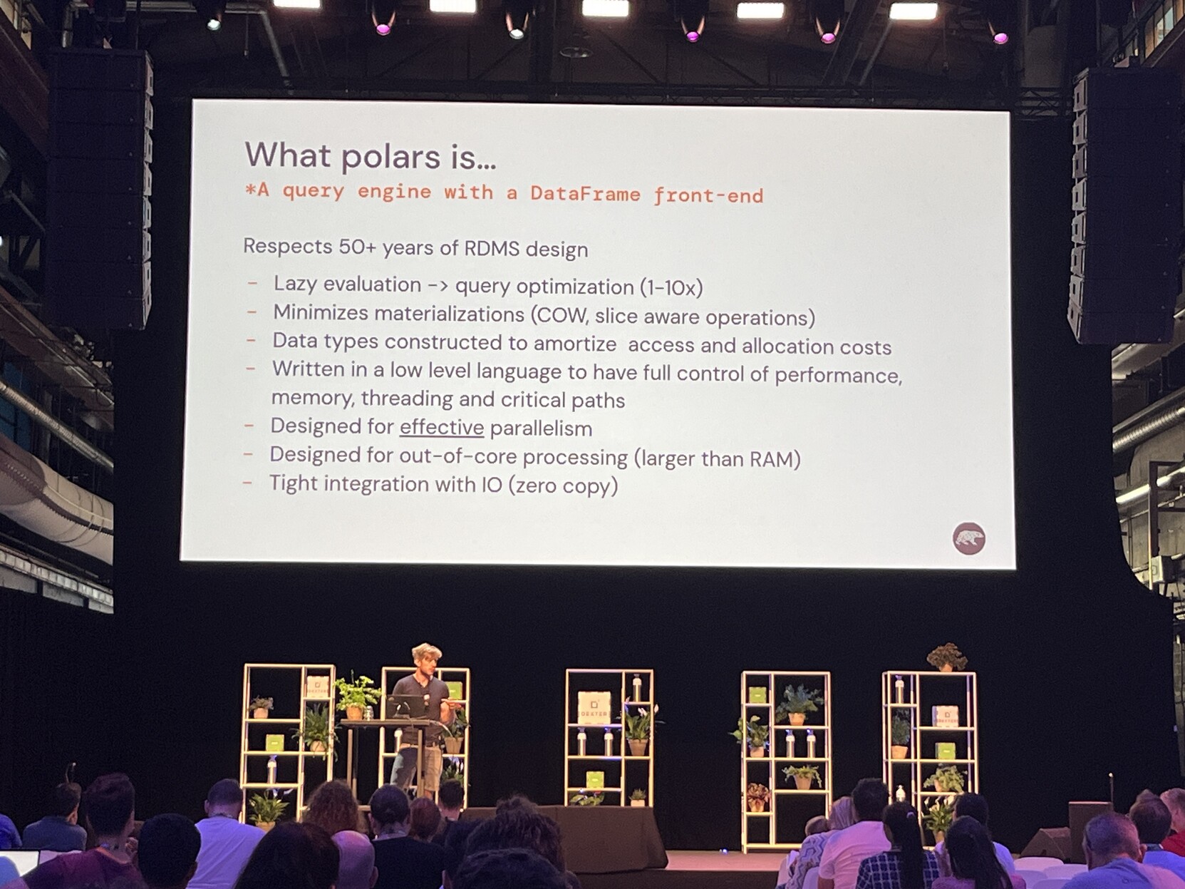 Photo of a speaker under a giant screen showing a slide titled "What polars is..."