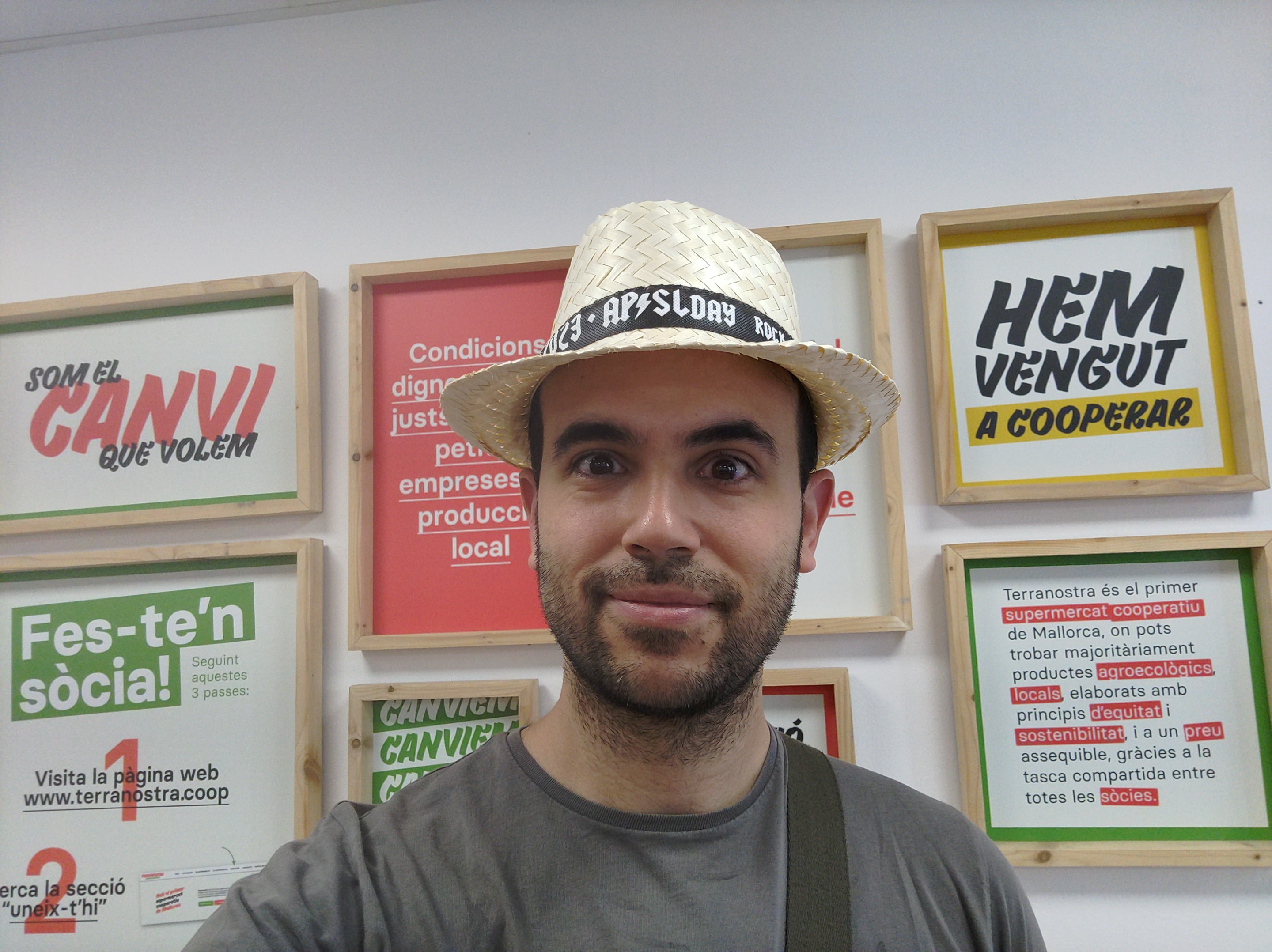 Selfie de hombre con sombrero ridículo mirando a cámara pero feliz de estar en un supermercado cooperativo